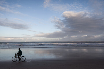 Fototapeta premium Man riding a bike in the beach with ocean background - Moreré, Bahia, Brazil