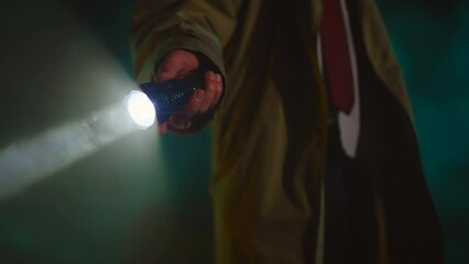 crime scene unrecognizable detective in a raincoat and hat with a flashlight looking for clues or retro style 1950