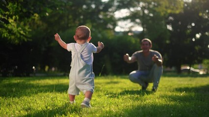 baby first steps. happy family a kid dream concept. baby son goes to his father in the park learns to walk first steps. baby first steps in nature. father teaches son lifestyle to walk