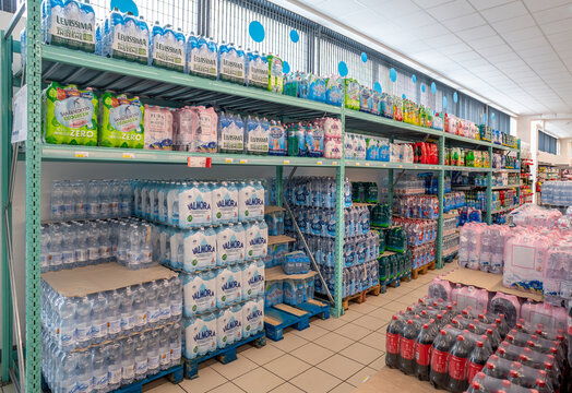 Italy - June 22, 2023: Plastic bottles of water and soft drinks on pallets and shelves for sale in Italian discount store supermarket