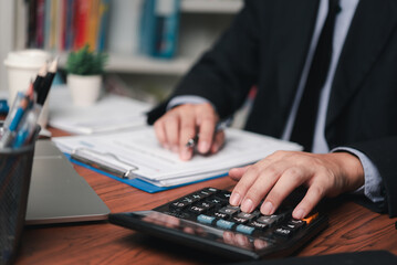 businessman working accountant document graph and chart on desk using calculator for calculate finance report in office.