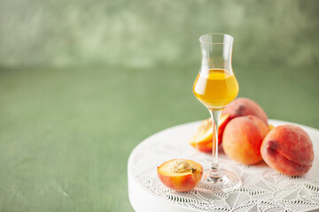 Peach liqueur in grappas glasses and fresh peaches on the table. Copy space