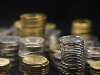 closeup shot of rows of gold and silver coins arranged and stacked in towers of different size isolated in a black background