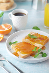 Fototapeta premium Sandwiches with marmalade, orange juice and coffee ready for breakfast