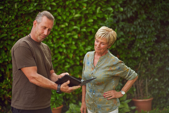 Craftsman being a gardener talking to a female senior customer holding a digital tablet making an offer