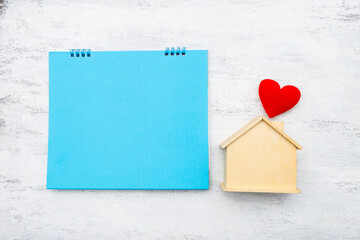 Blank blue card with wooden house model and red heart on white background, buy new hosue, property investment, real estate business