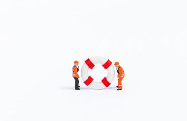 Two miniature worker in safety suite with lifebuoy isolate on white background, safety industry