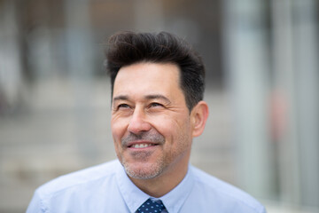 Obraz premium Smiling older businessman standing outside in city