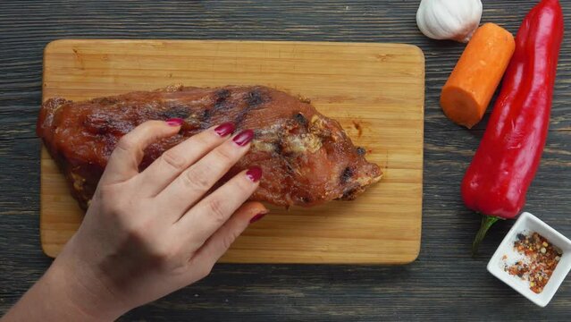 Hand inserts pieces of carrot, garlic and pepper into a hole in a piece of meat 