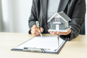 real estate agent hold the home model, sign and explain the business contract, rent, buy, mortgage, loan, or home insurance
