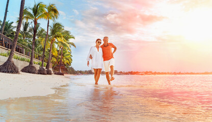 Couple in love hugging while walking on a sandy exotic beach. They have an evening walk by...
