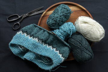 Turquoise green white wool knitted sweater on a needle with yarn balls and vintage scissors,...