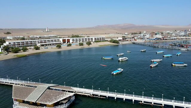 Aerial shot drone flies over pier at edge of boat marina in Paracas, Peru