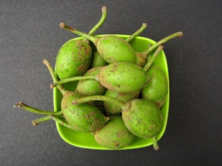 Mahua or Madhuca longifolia fruits in a bowl on black background 