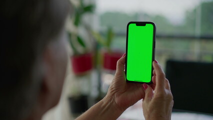 Senior person hands holding smartphone with Chroma key greenscreen. Older person looking at phone screen