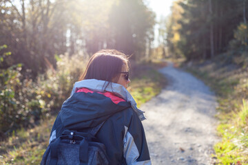 Young woman with backpack hiking in autumn forest. Hiking concept.