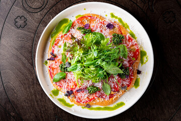 Fresh healthy tomato carpaccio with balsamic vinegar, cheese and salad