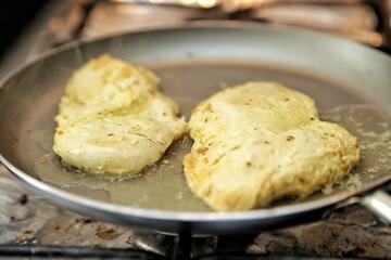Filé de frango na frigideira fritando com tempero e óleo.