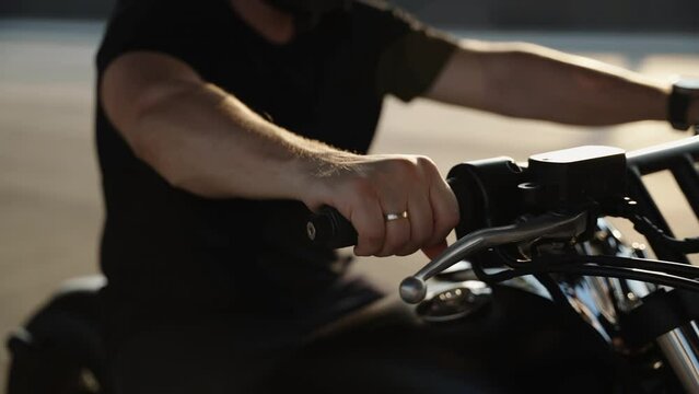 A man's hand pedals the gas on a bike. A sunny day for riding a bike.