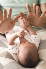 A baby playing with his father's hands