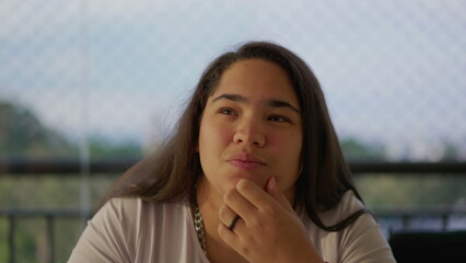 One pensive young woman pondering solution with hand in chin. A thoughtful ethnically diverse Asian adult girl in 20s thinking deeply