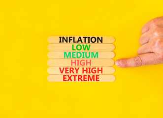 High inflation symbol. Concept word Inflation low medium high very high extreme on wooden sticks. Businessman hand. Beautiful yellow background. Business time to high inflation concept. Copy space