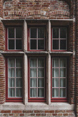 An old red wooden window in a orange brick house