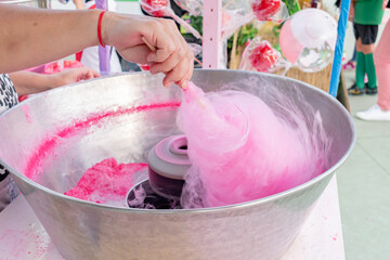 Woman making pink cotton candy at a street fair food stall.