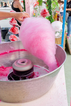 Woman making pink cotton candy at a street fair food stall.