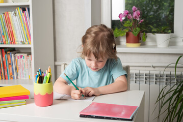 Back to school. Girl sits at a table with books and a notebook and does her homework. Children learning at home