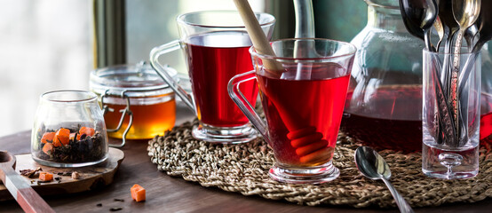 A narrow view of hot hibiscus tea servings along with honey.