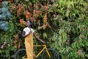 Young woman with an ice cream and a yellow bicycle next to a vertical garden. Concept: Gardening, lifestyle, outdoors