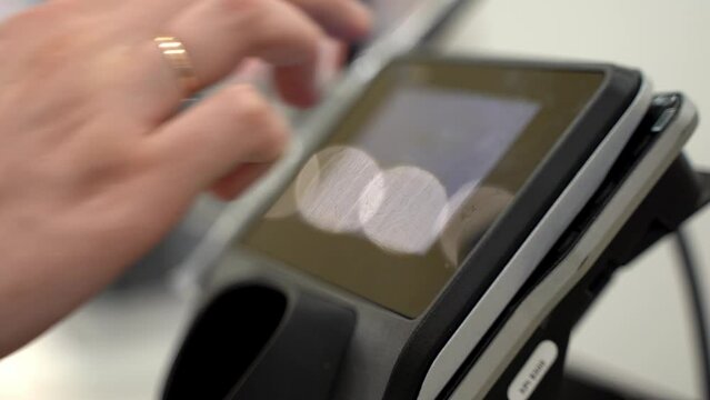 Close up of hands and card taping on screen to buy products. Fingers press buy button. Closeup of people paying items at self check out counter