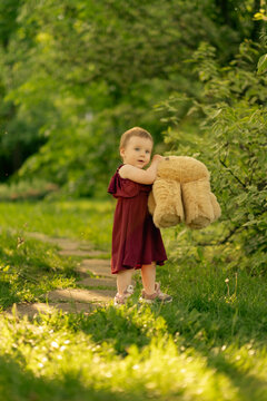 radiant photo of a toddler in a park, bearing a cuddly oversized teddy bear, experiencing her first adventures. adventures, and early-life experiences.