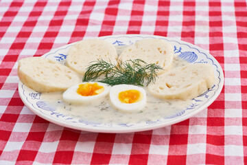 Creamy dill sauce with czech bread dumplings and soft boiled egg served on the vintage blue onion porcelain plate. Traditional seasonal dish typical for cuisine of Czech Rebublic or Eastern europe.