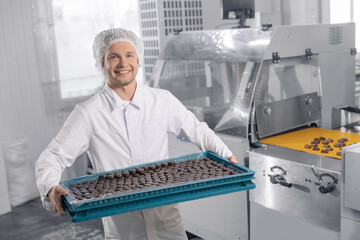 Worker man with sweets candy. Concept modern chocolate factory production line, food industry