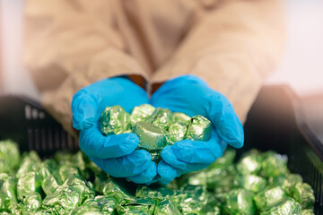 Closeup chocolates sweets candy in hands of worker. Concept modern chocolate factory production...