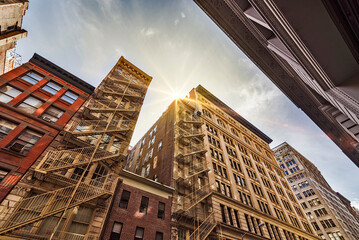 Narrow alley with Old apartment buildings and fire escapes on a sunny day in Midtown Manhattan, New...