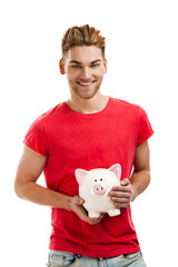 Fototapeta na wymiar Handsome young holding a piggybank and smiling, isolated over a white background