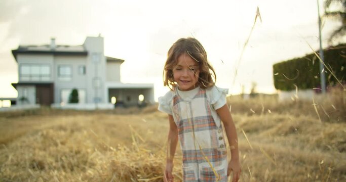 Happy moments of life, a child, a girl throws hay into the top. The child is happy and jumping and fooling around in nature in the village. High quality 4k footage