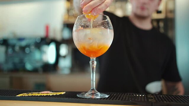 barkeeper prepare orange aperol spritz cold cocktail with ice in glass