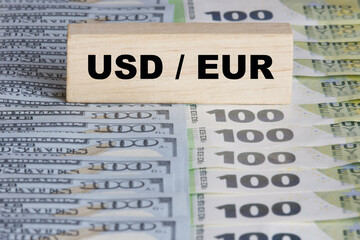 Inscription USD EUR on wooden block, one hundred dollar and euro bills on the background. Concept for money exchange, forex, currency value.