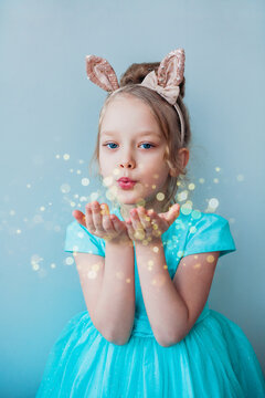 Portrait of a cute little girl blowing star dust. Christmas, birthday, party time.