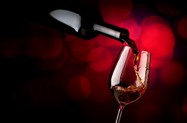 Fototapeta na wymiar Wine pouring in wineglass on a vinous background