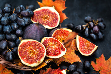 Autumnal fresh ripe figs and purple grape on dark  background