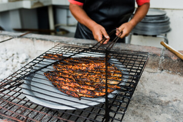 hands of mexican man cooking grilled fish traditional from Acapulco Mexico or barbecued fish called...