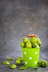 Organic fresh raw brussels sprouts in a metal bucket on gray background, copy space