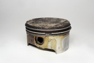 engine piston with black sludge of deposit formations on flat head surface. gas-tight seal compression rings between the ring lands. showing hole for wrist pin