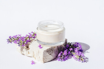 Lavender cream in a jar on stone podium in sunlight. Natural cosmetics, aromatherapy concept. Closeup