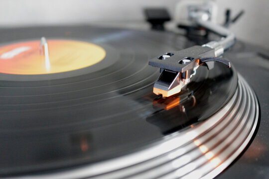 Turntable with focus on the needle touching the black vinyl. Background is out of focus.